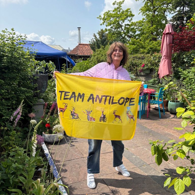Team Antilope Vlag Pien staat in de tuin met de gele Team Antilope-vlag
